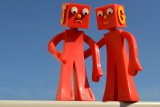 Twee rode speelgoedrobots die elkaar troosten